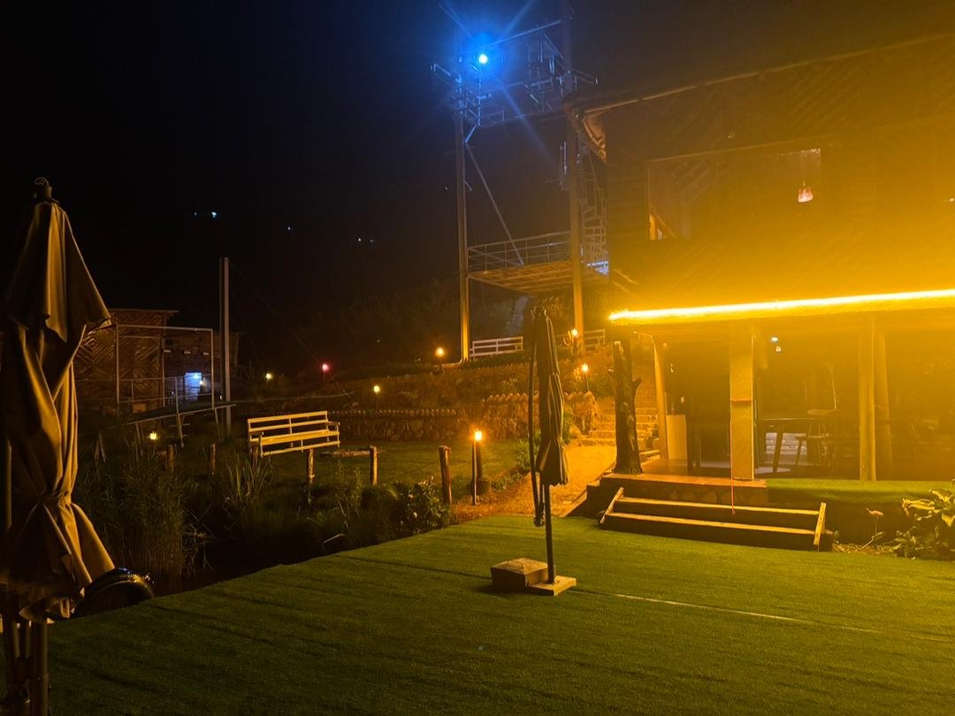 Nighttime front view of Bunyonyi Luxury Resort with glowing lights reflecting beautifully on Lake Bunyonyi.